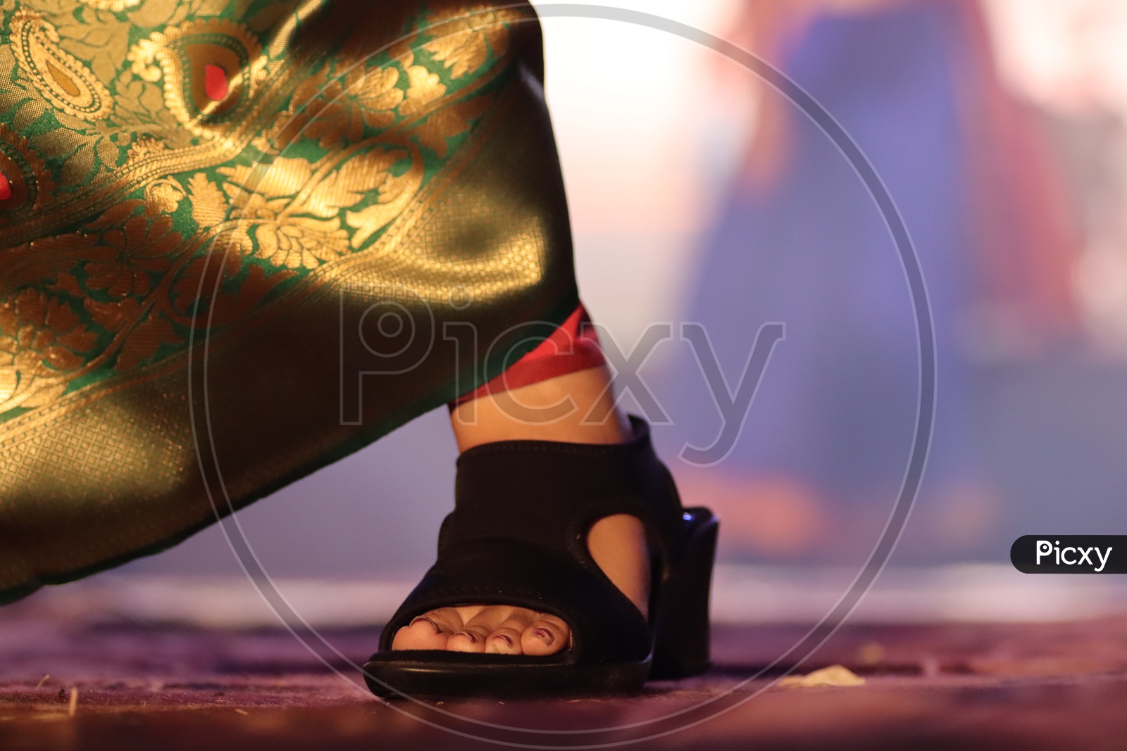 Feet Closeup Of a Woman Wearing Saree  Walking On Stage With Heel Sandal Footwear And Neon Lights