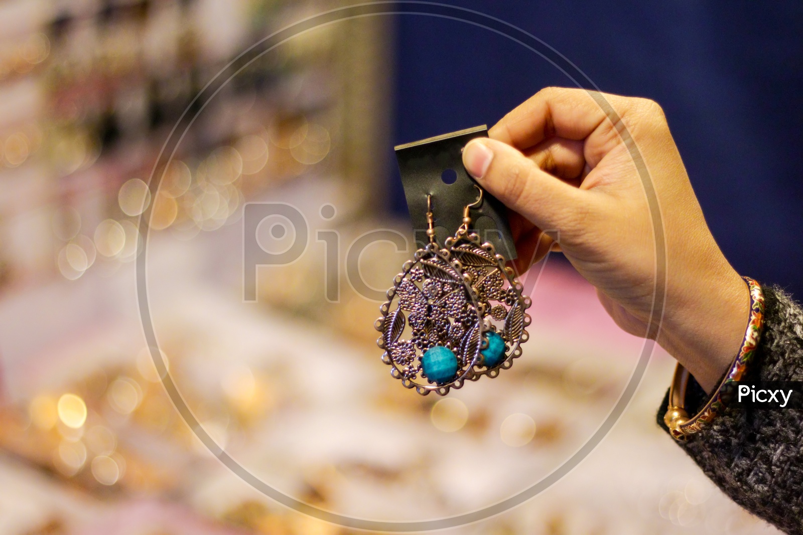 Hand Of A Lady Selecting Ear Rings Metal Junk Jewellery At A Shop.