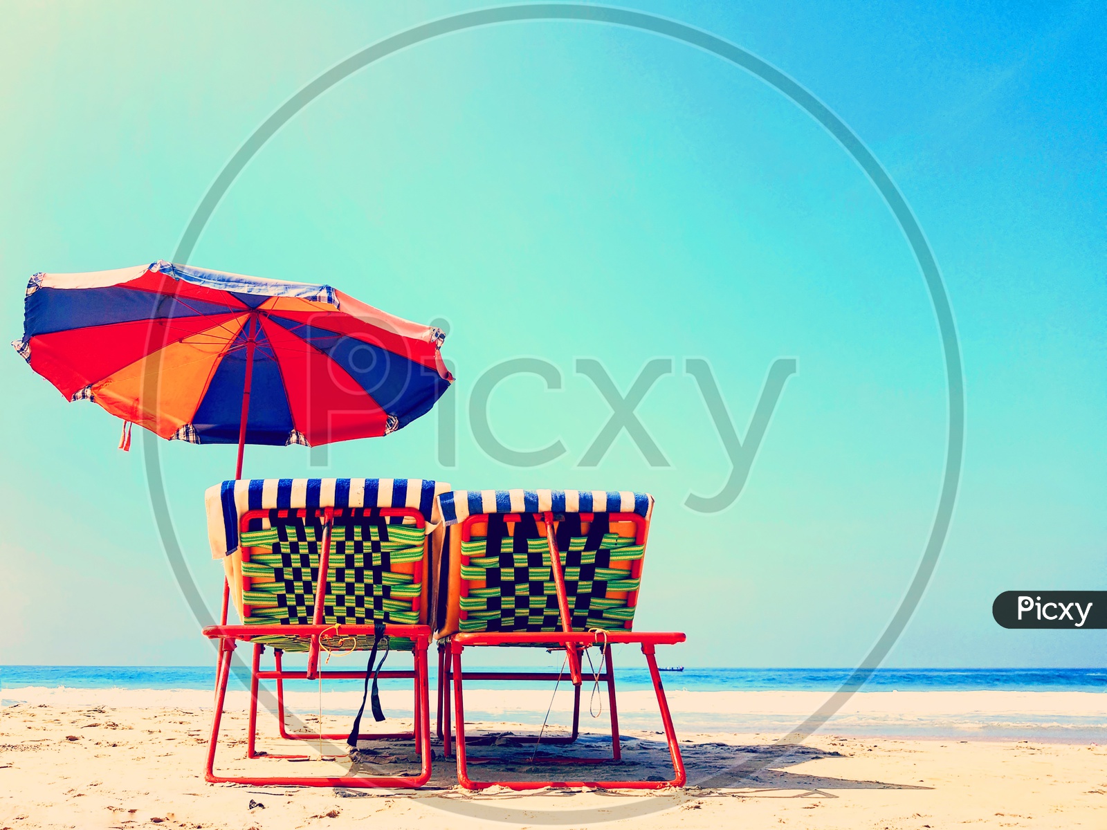 Resting Chairs With A Colourful Umbrella On A Sunny Tropical Beach