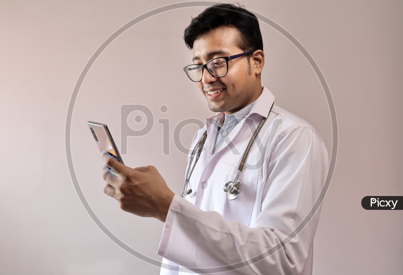 Male Indian Doctor In White Coat And Stethoscope using Smart Phone or Mobile