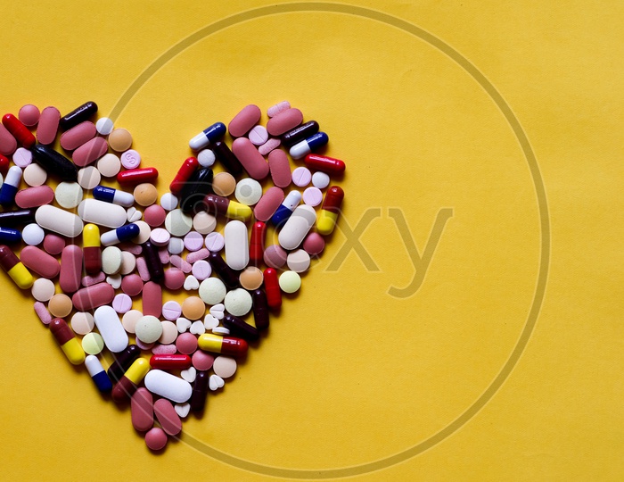 Medicine Pills Tablets Capsules In Shape Of Human Heart In Yellow Background With Space For Text