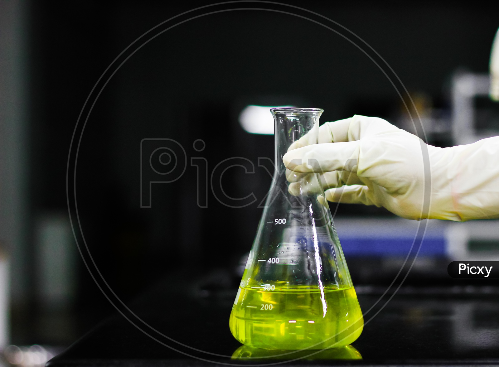Scientist Holding A Glass Conical Flask In A Gloved Hand In Chemistry Laboratory