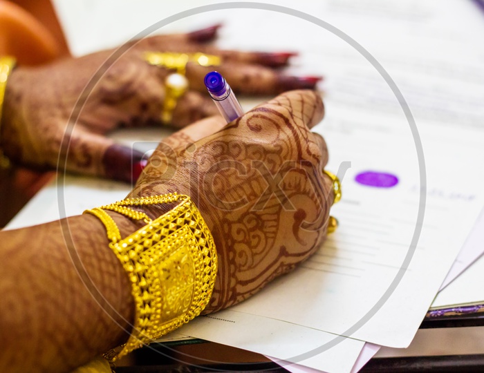 A Newly Married Indian Bengali Wife With Golden Ornament And Bracelet Signing Marriage Registration Form
