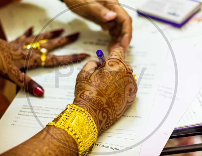 A Newly Married Indian Bengali Wife With Golden Ornament And Bracelet Signing Marriage Registration Form