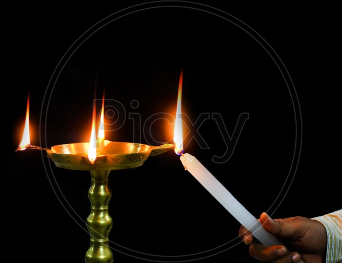 Oil Brass Lamp Diya Being Lit By A Candle For Inauguration Ceremony Holy Worship In Isolated Dark Black Background