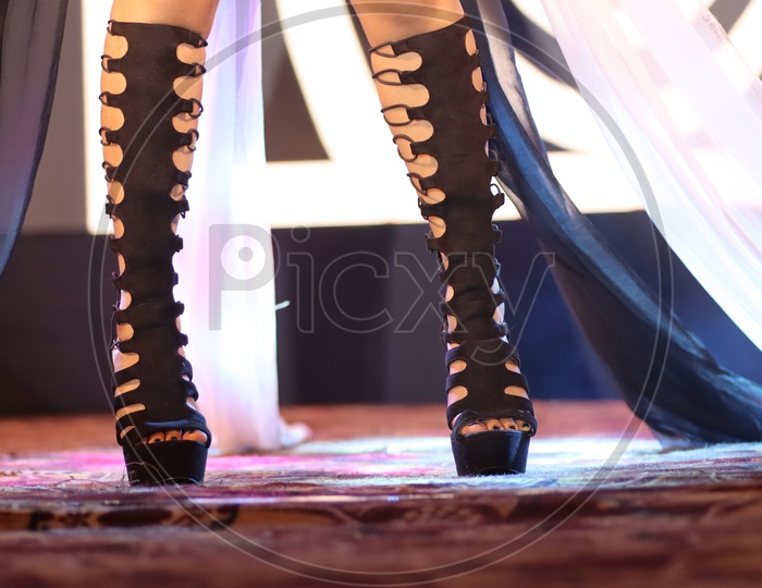 feet of a dancer on stage doing hip hop dancing stance with background neon lights