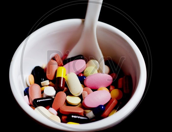 Bowl Of Medicine Pills Tablets Capsules In Black Background