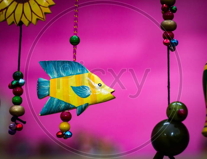 Yellow Wooden Fish With Blue Fins Suspended By Beaded String