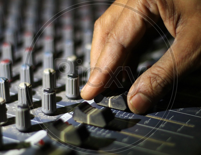 Hands Operating Knobs Of Light And Sound Board Console At A Concert Theater