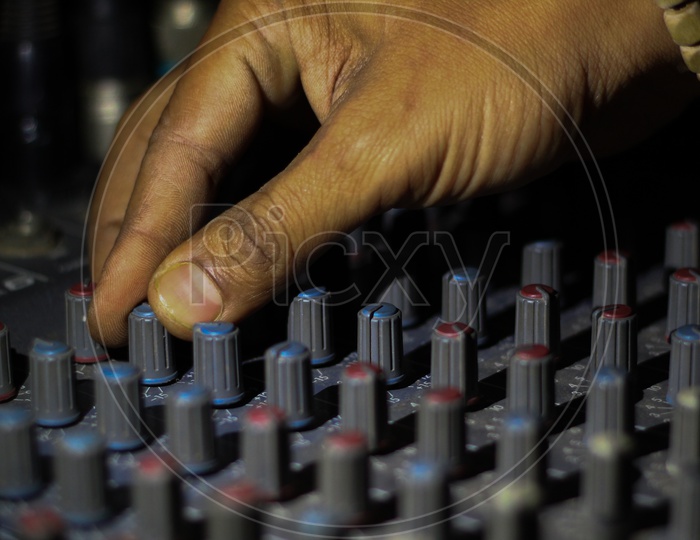 Hands Operating Knobs Of Light And Sound Board Console At A Concert Theater