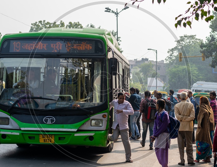 People getting on the bus and getting down from the DTC, Delhi Transport Corporation bus