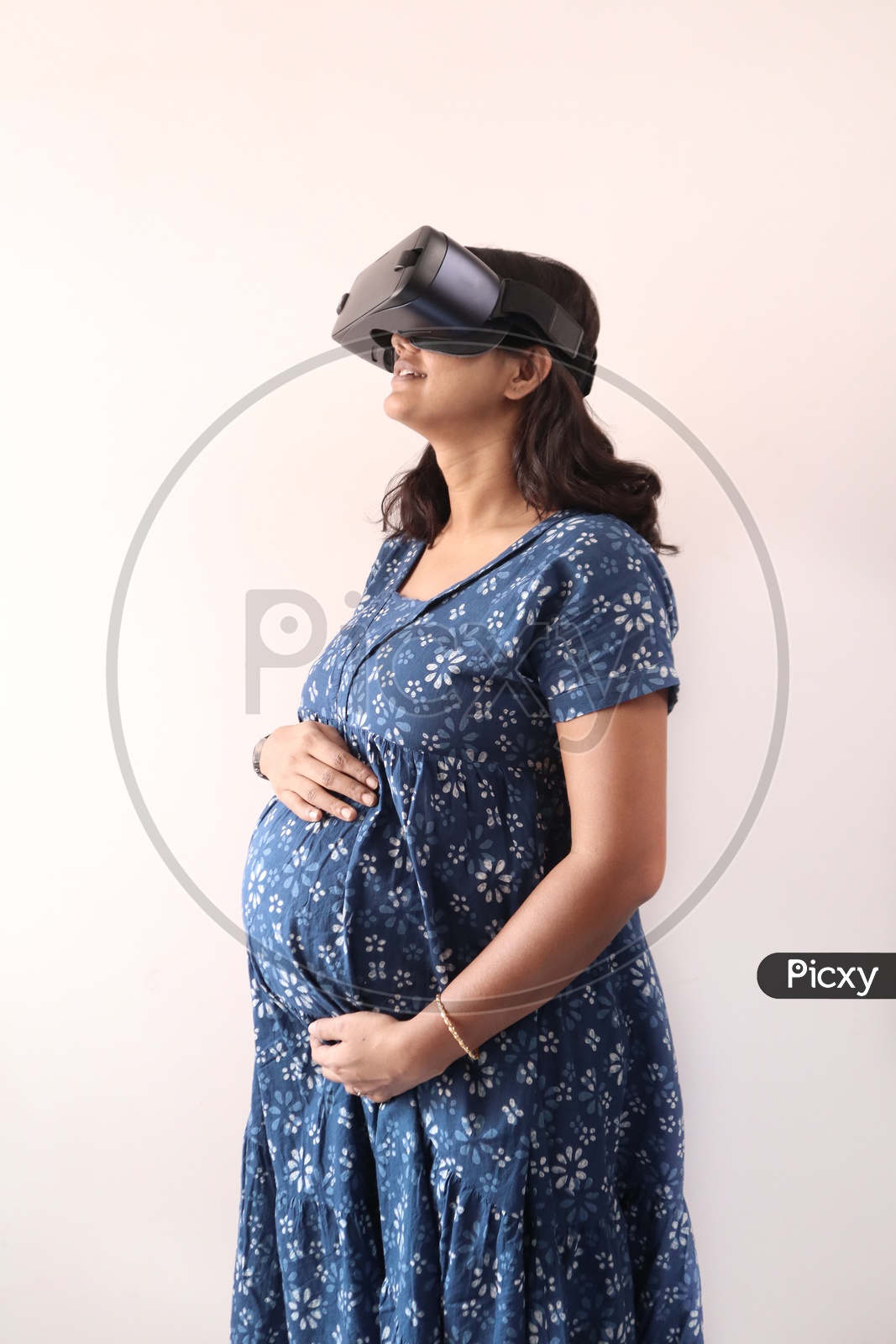 A Pregnant Woman With Hands On Belly And Virtual Reality Glass In Eye In Blue Dress.