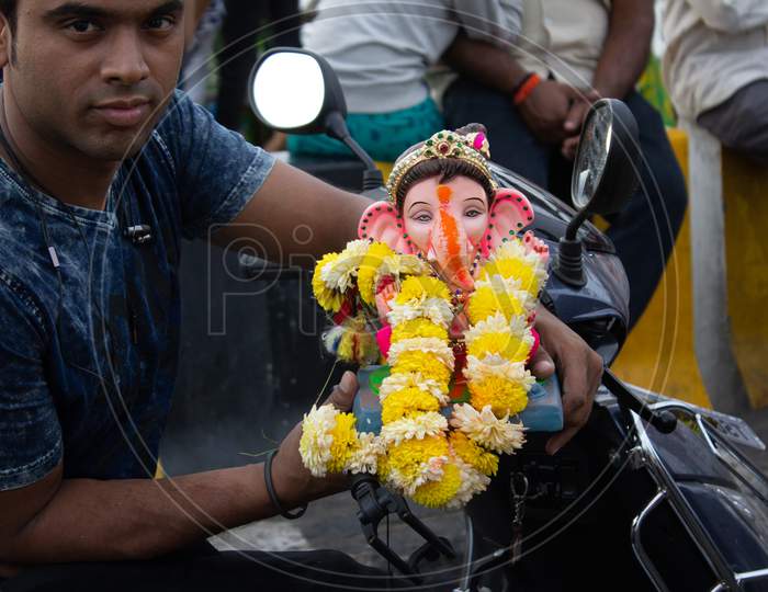 A Man Holding Ganesha Idol in Hand