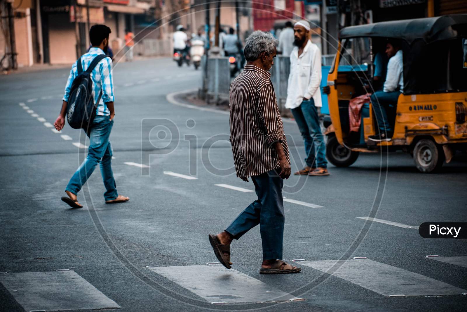 An Old Man Crossing Zebra Crossing At a Road