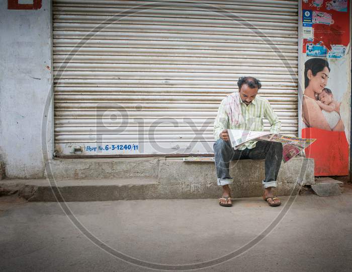 A Man Reading newspaper By Sitting On Road