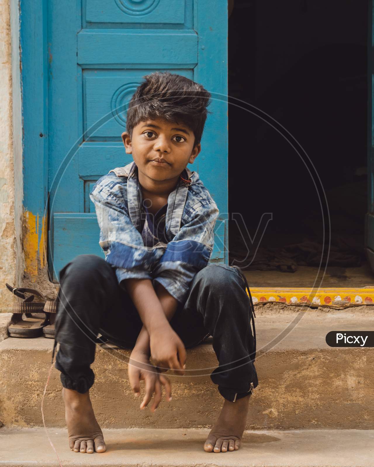 Indian Boy Sitting At a House Door Step