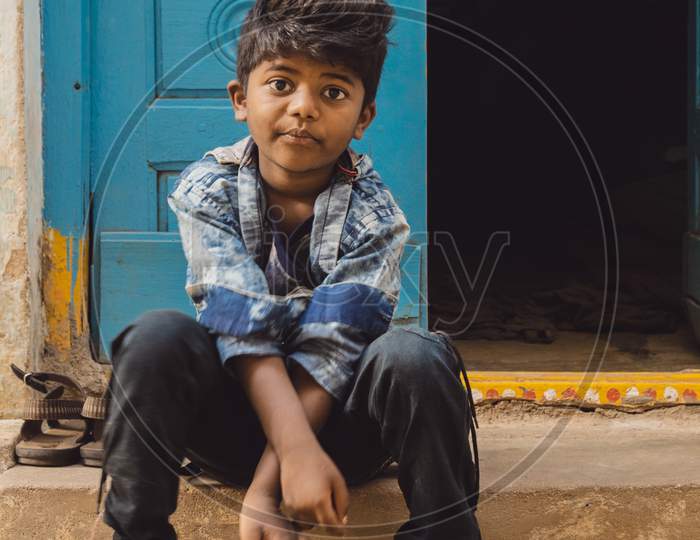 Indian Boy Sitting At a House Door Step