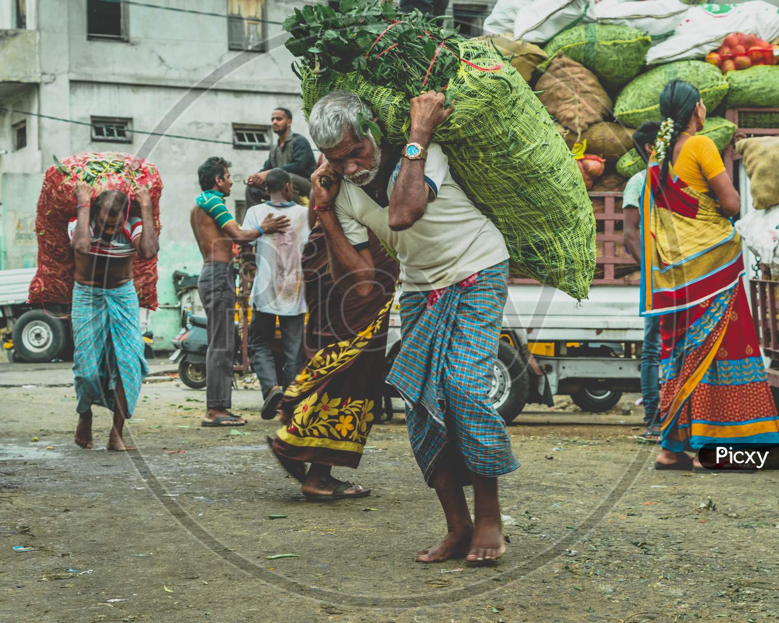 A Man Carrying Vegetable Bags At a Market