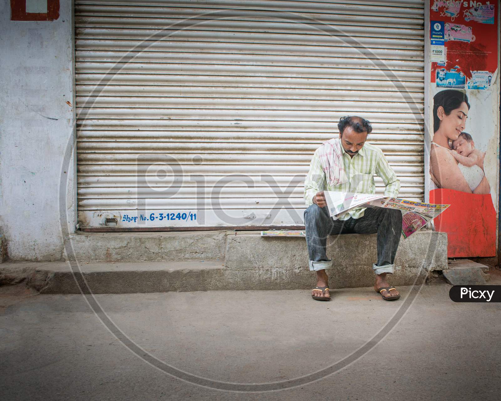 A Man Reading newspaper By Sitting On Road