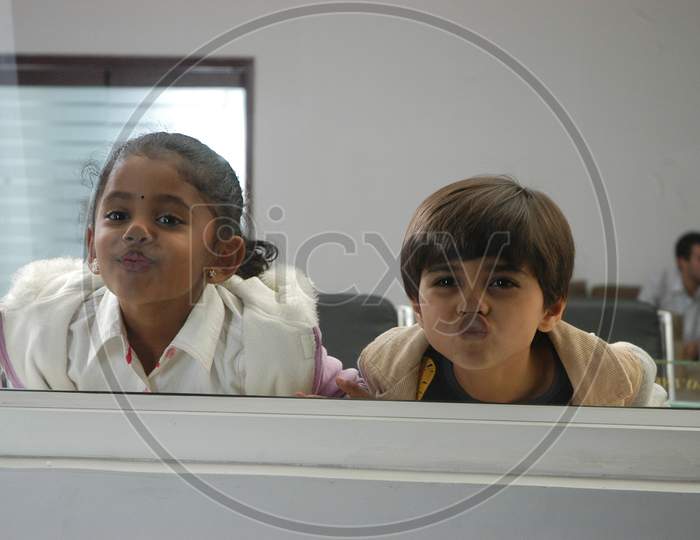 Children Looking Through An Window Glass