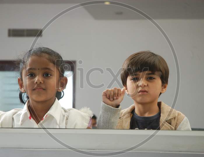 Children Looking Through An Window Glass