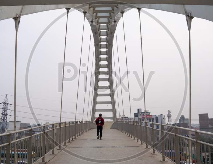 A man walking at a foot over bridge over Outer ring road Delhi
