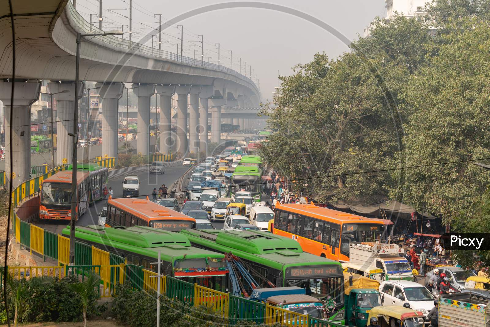 Heavy traffic merging, resulting in traffic jam congestion and Delhi metro passing over the road