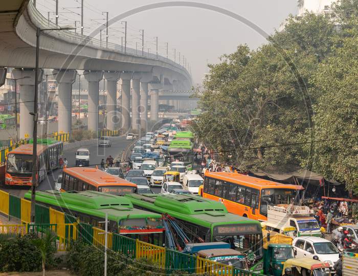 Heavy traffic merging, resulting in traffic jam congestion and Delhi metro passing over the road