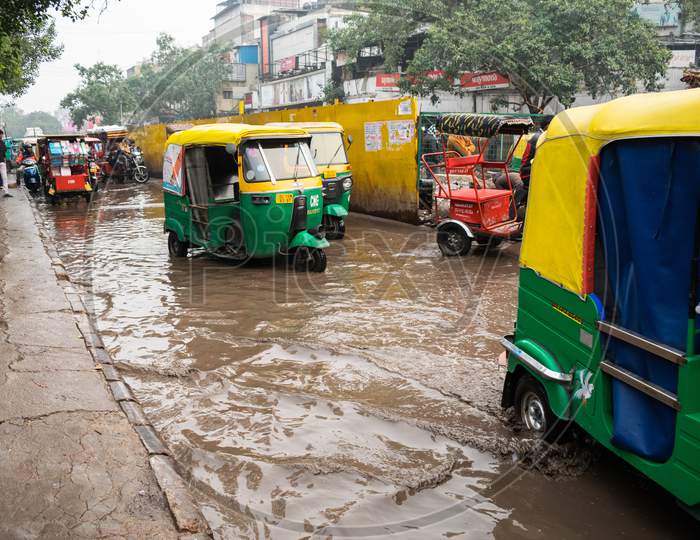 Auto rickshaws and other vehicles moving on the road filled with rain water