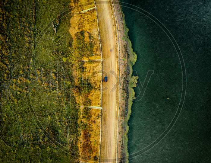Drone shot of village road, car and lake