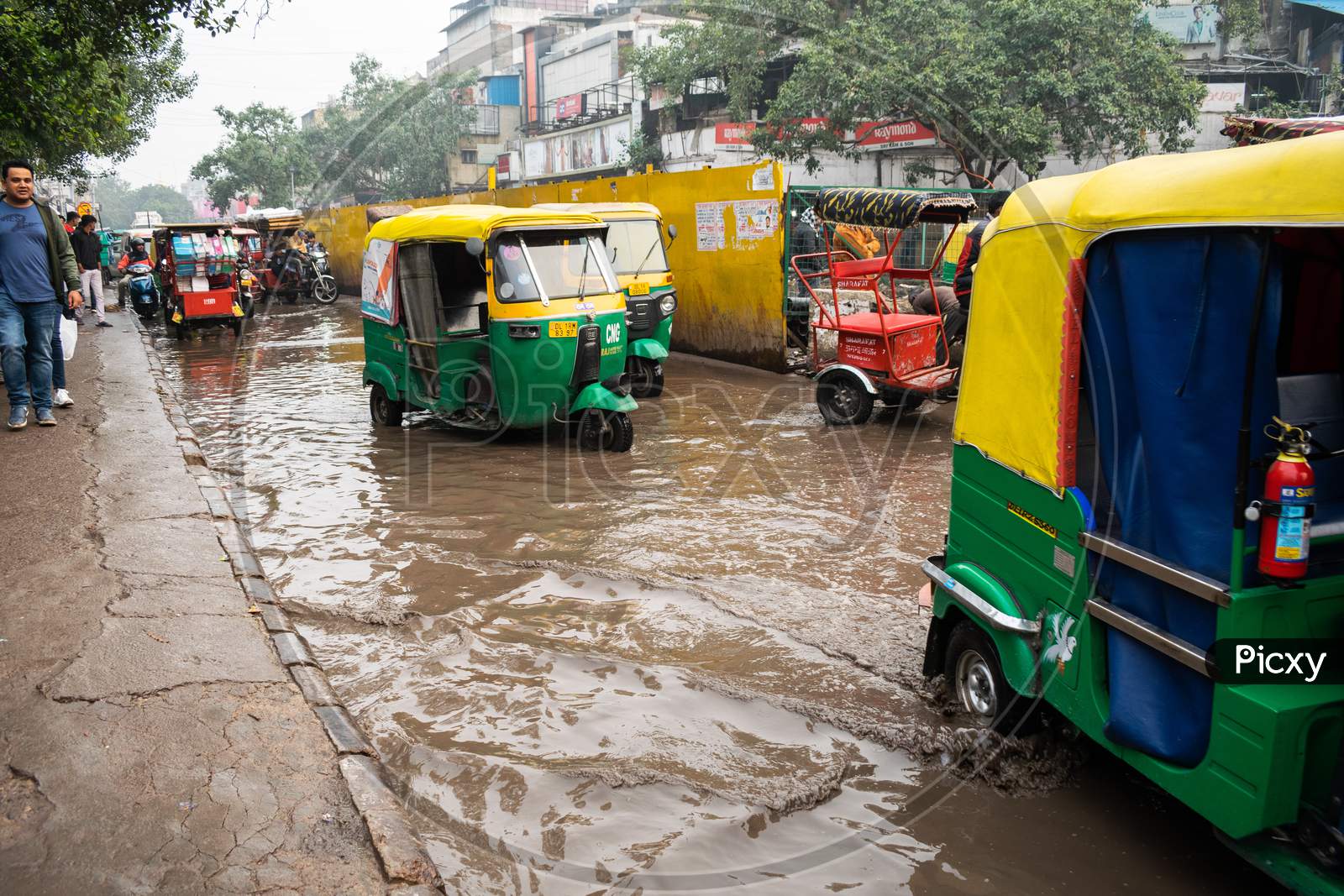 Auto rickshaws and other vehicles moving on the road filled with rain water