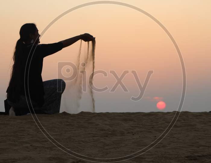 woman dropping sand at Sunset