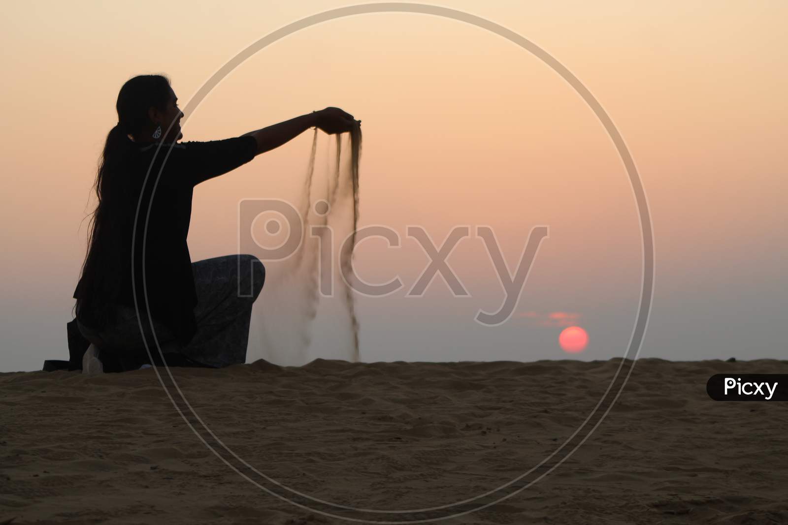 woman dropping sand at Sunset