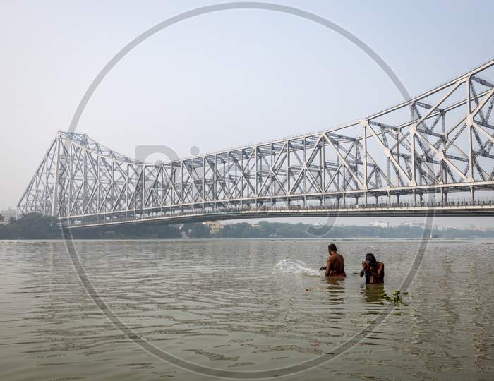 A View Of Howrah Bridge With People Taking bath In Hooghly River in kolkata