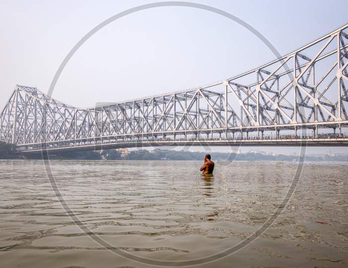 A View Of Howrah Bridge With People Taking Bath in Hooghly River  in Kolkata