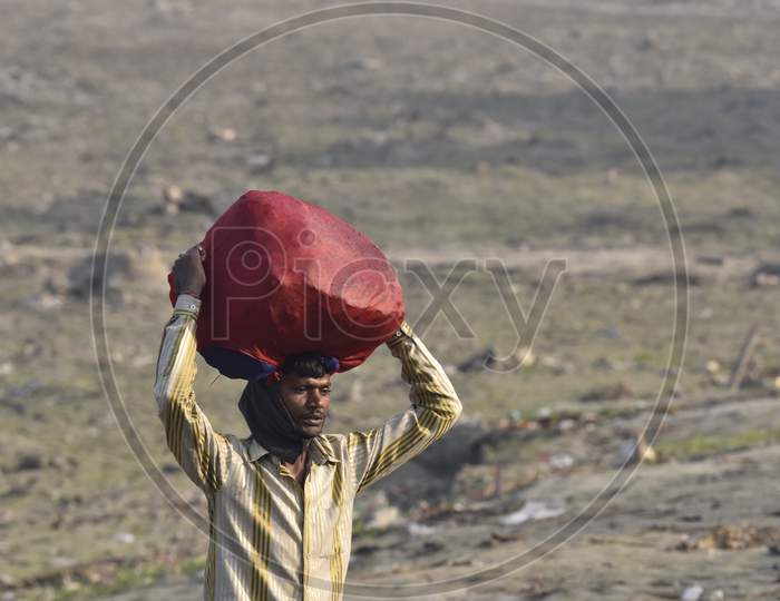 Indian Washer Man Carrying Clothes Bundles over His head on Bramhaputra River Bank In Assam