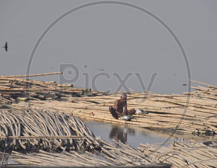 Boat Man Joining Bamboo Logs in order to Make a Wooden Floating Board For Carrying Heavy Good On River Bramhaputra in Assam