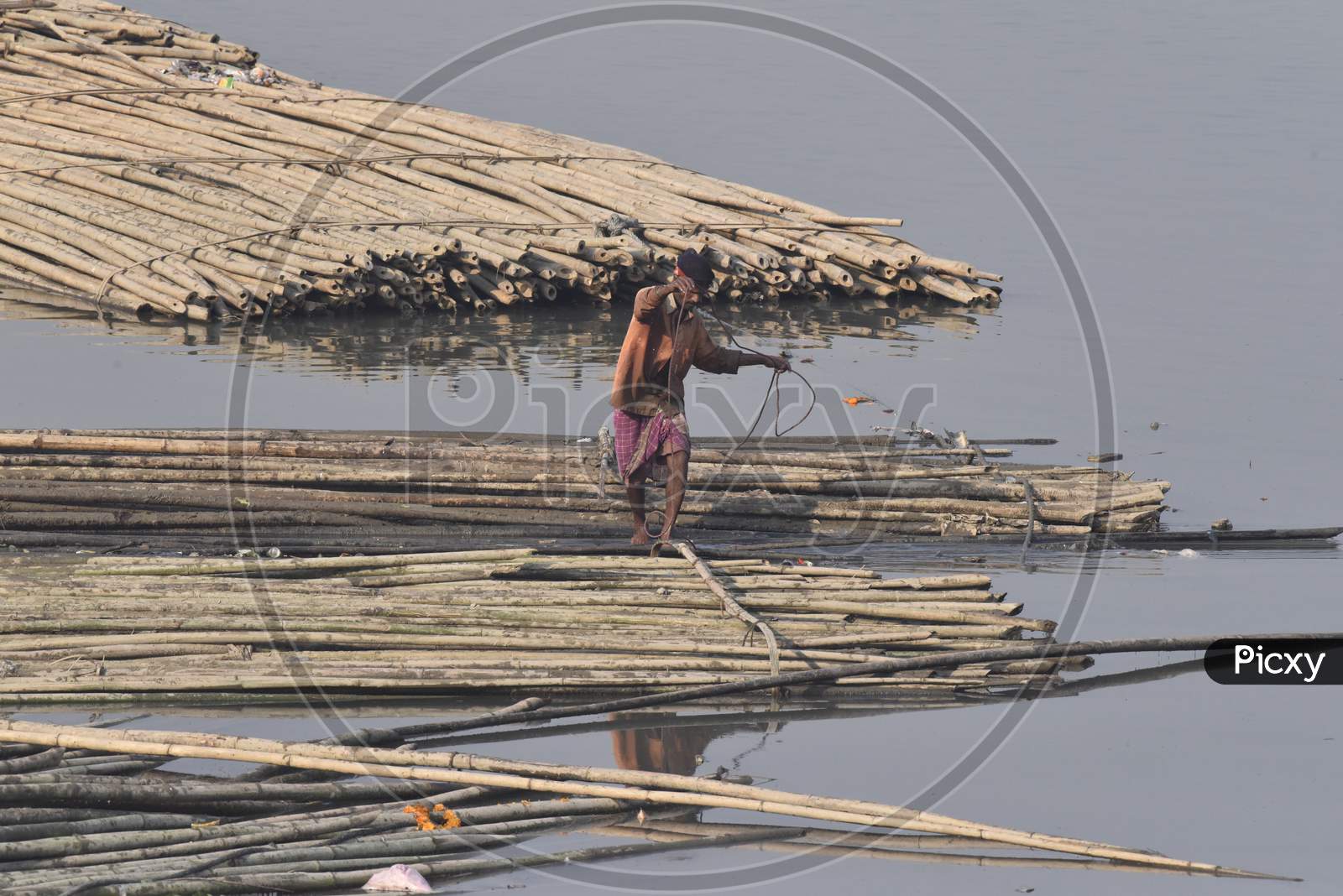 Boat Man Joining Bamboo Logs in order to Make a Wooden Floating Board For Carrying Heavy Good On River Bramhaputra in Assam