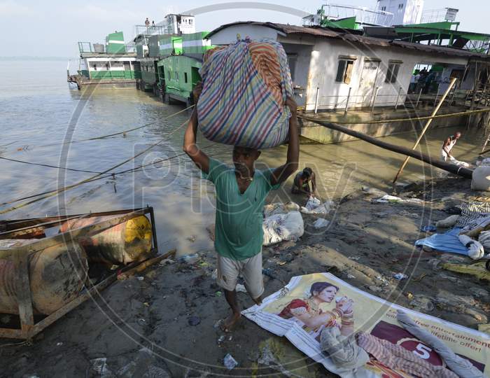 Indian Washerman or Dhobi Carrying Clothes Bundles From Bramhaputra River Bank in Assam