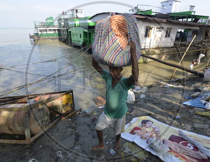 Indian Washerman or Dhobi Carrying Clothes Bundles From Bramhaputra River Bank in Assam