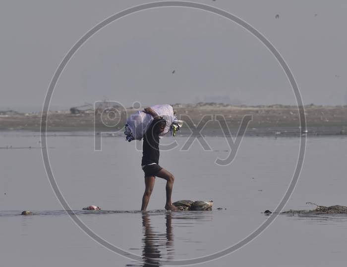 Indian Washer Man Or Dhobi Carrying Clothes Bundle After Washing In Bramhaputra River In Assam