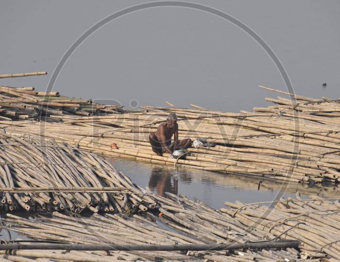 Indian Man Washing Clothes By Sitting on a Floating Wooden Log Board on Bramhapura River in Assam