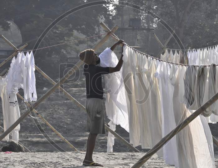 Indian Washer Man or Dhobi Drying Washed Clothes on The Bank Of Bramhaputra River In Assam