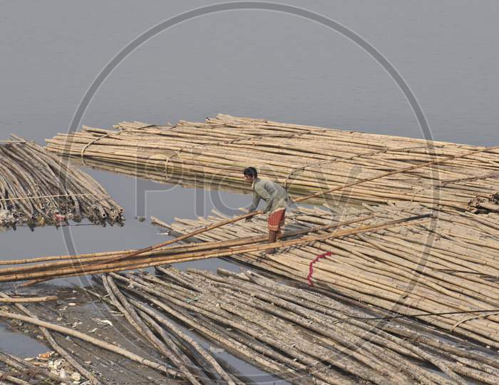 Indian Man Washing Clothes By Sitting on a Floating Wooden Log Board on Bramhapura River in Assam