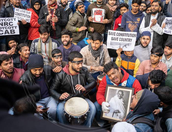 A Student holding picture of Mahatma Gandhi and others holding slogans during protest against CAA and NRC outside Jamia Millia Islamia, A Central University in New Delhi