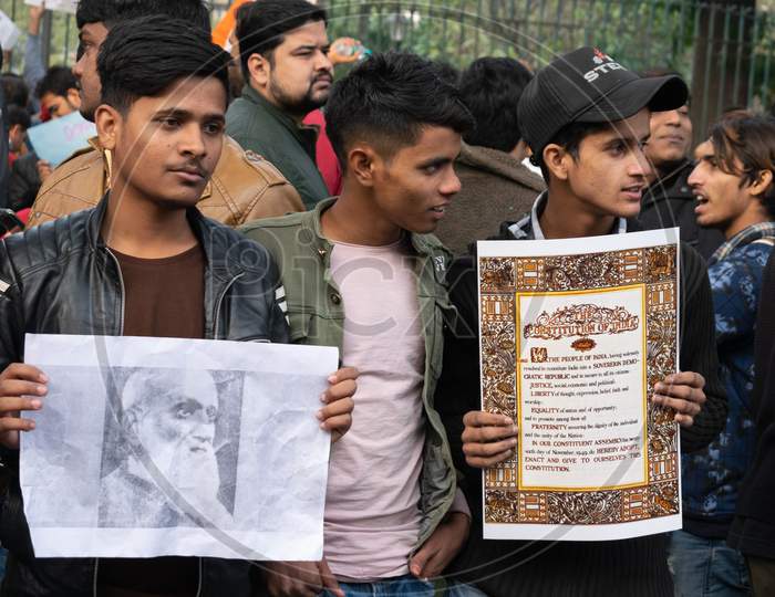 A boy holding The Preamble of Indian Constitution and others Protesting Against Caa And Nrc Outside Jamia Millia Islamia University