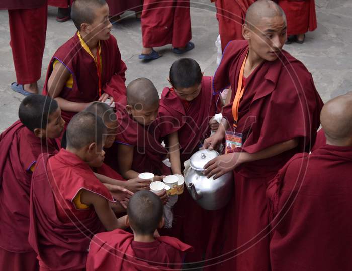 A Buddhist Monk Serving Water To Child Monks At a Buddhist Monastery