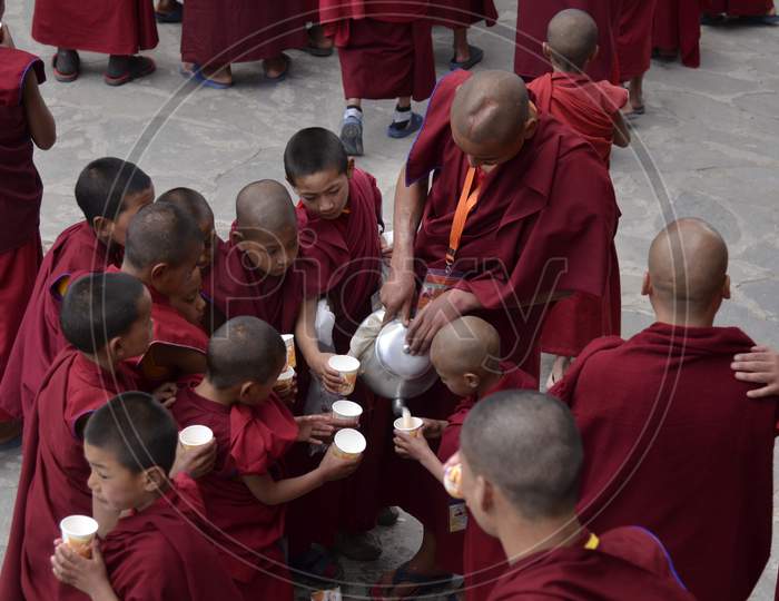 A Buddhist Monk Serving Water To Child Monks At a Buddhist Monastery