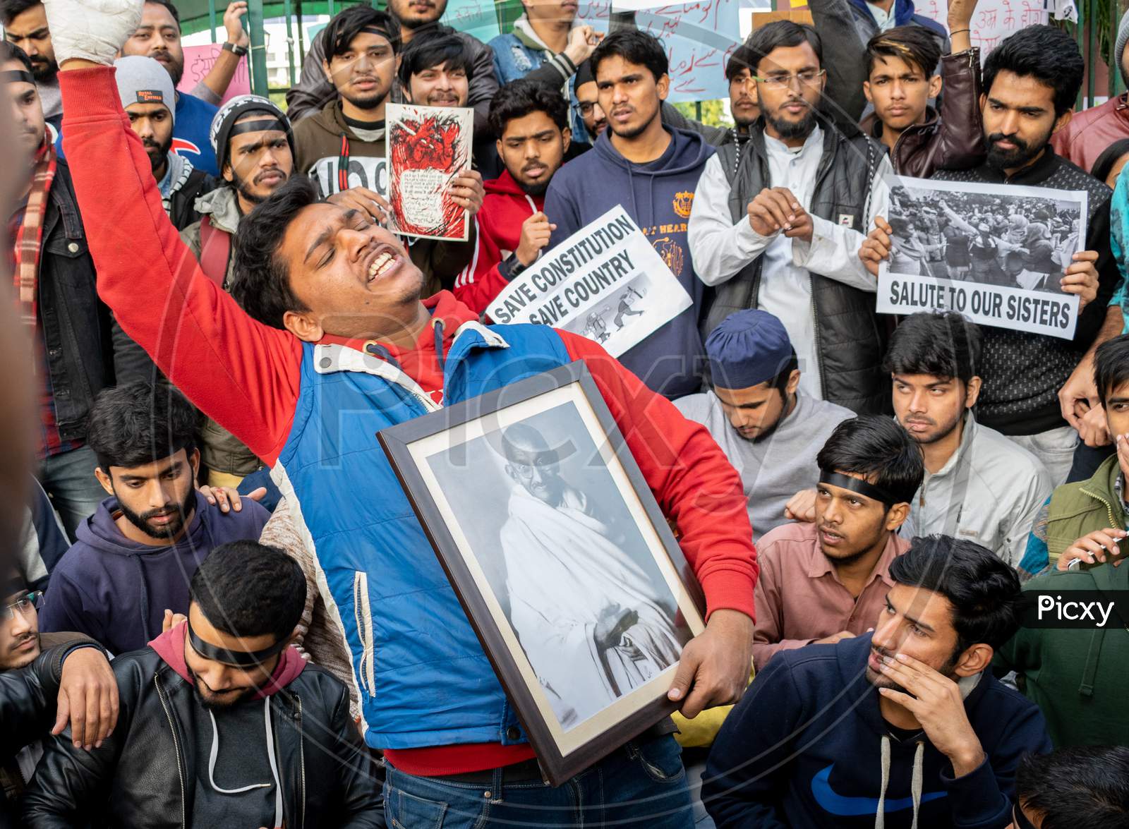 A Student holding picture of Mahatma Gandhi and others holding slogans during protest against CAA and NRC outside Jamia Millia Islamia, A Central University in New Delhi