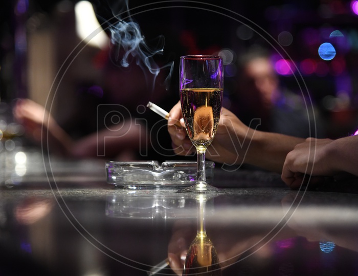 A Wine Glass With a Man Holding Cigarette in Hand Closeup